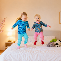 2 Kinder hüpfen auf Bett in bunten Babauba-Pyjamas