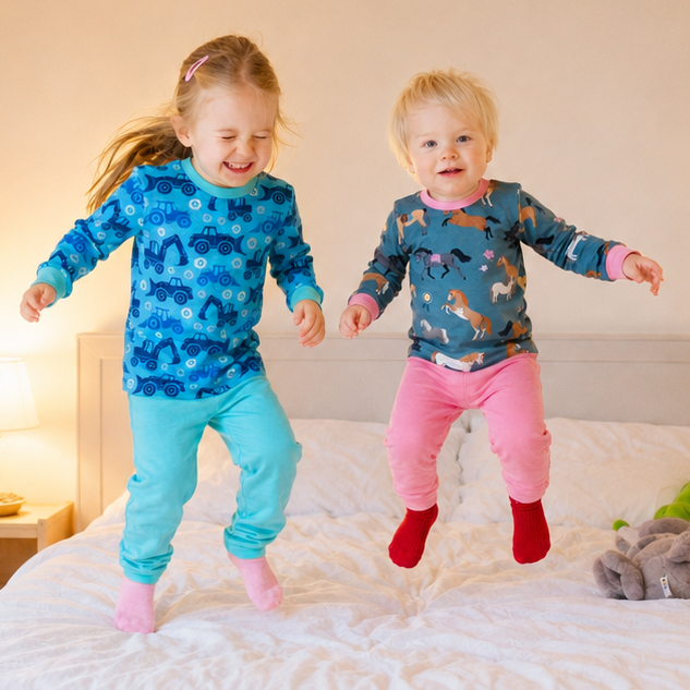2 Kinder hüpfen auf Bett in bunten Babauba-Pyjamas